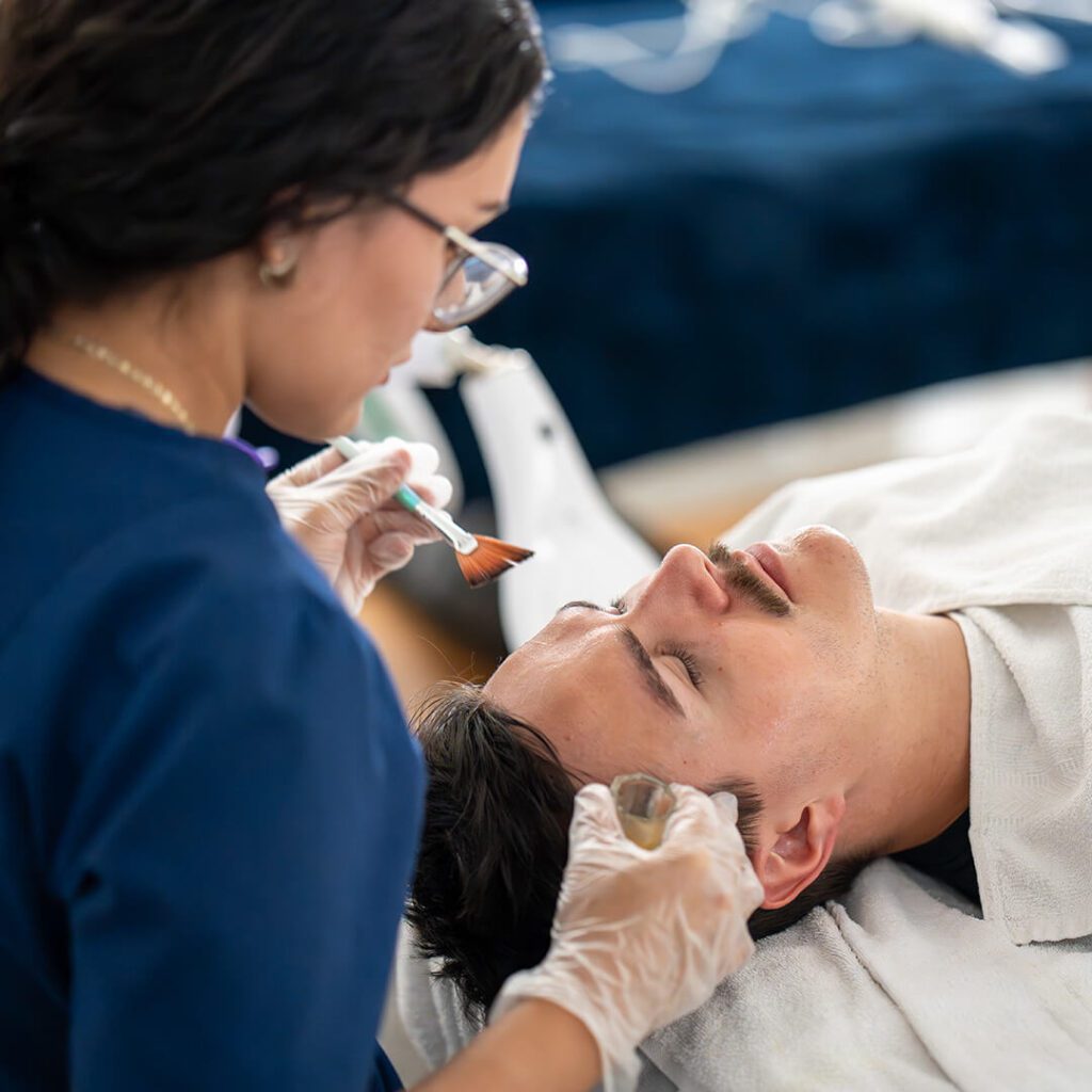 A client receiving a hydrating facial treatment at IMAj Institute, with esthetician applying a moisture-rich mask.