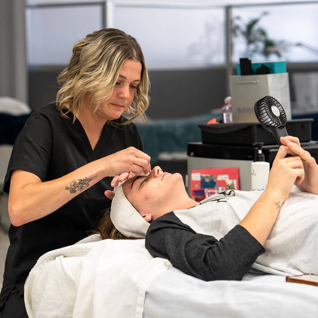 An esthetician consulting with a client about their skincare goals and facial options at IMAj Institute.